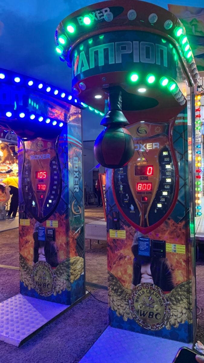Illuminated arcade game machines with neon green and blue lights in a gaming venue at night