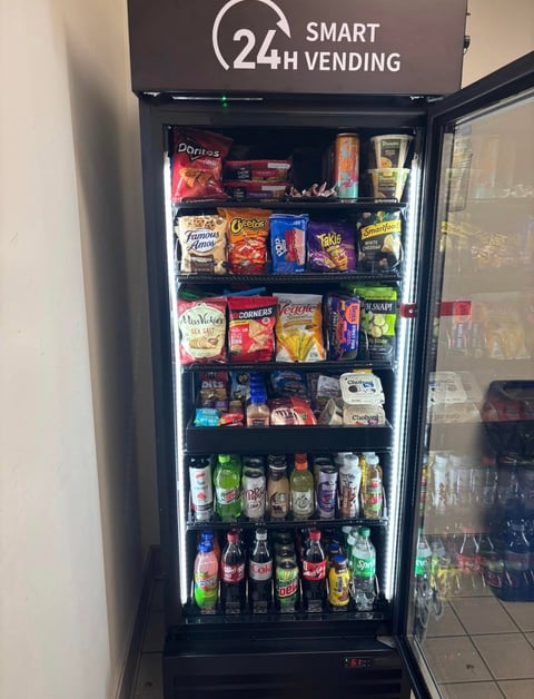 24-hour smart vending machine stocked with snacks, candy, and beverages behind glass door