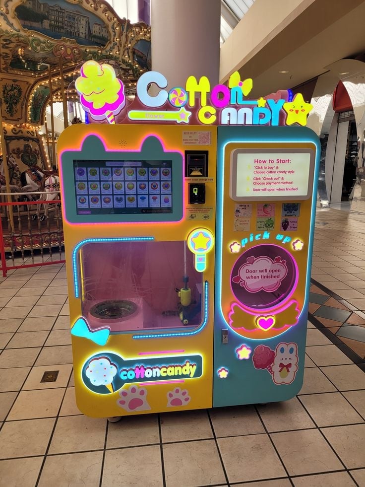 Colorful Cotton Candy vending machine with bright yellow and blue exterior, interactive touchscreen, and candy dispenser in a mall