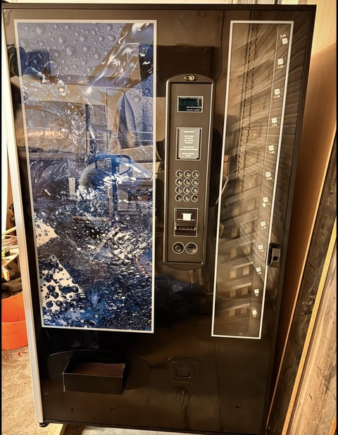 Black vending machine with lunar landscape display and illuminated product shelves on the right side