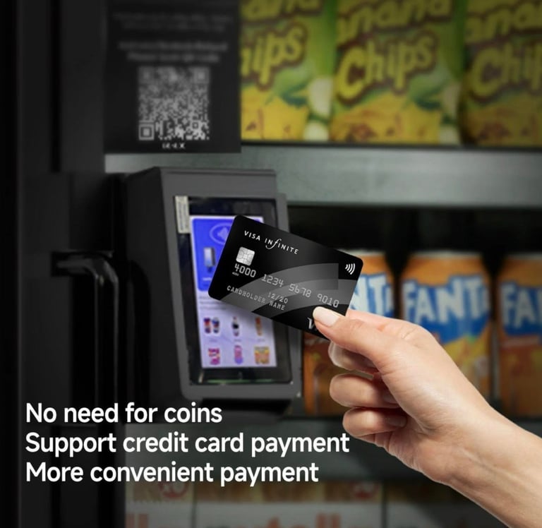 Hand holding a black credit card to a vending machine reader, showing contactless payment capability for snacks and beverages