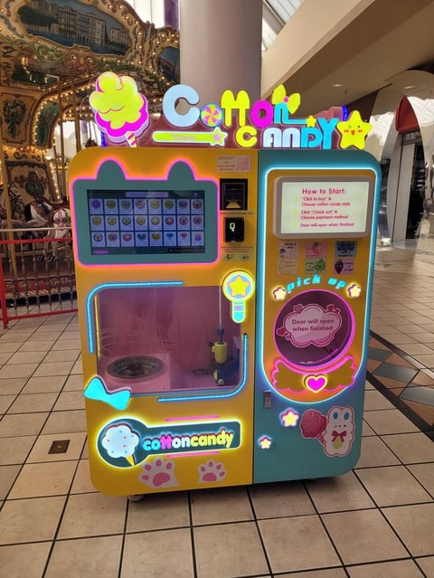 Colorful Cotton Candy vending machine with neon accents and game interface in a shopping mall